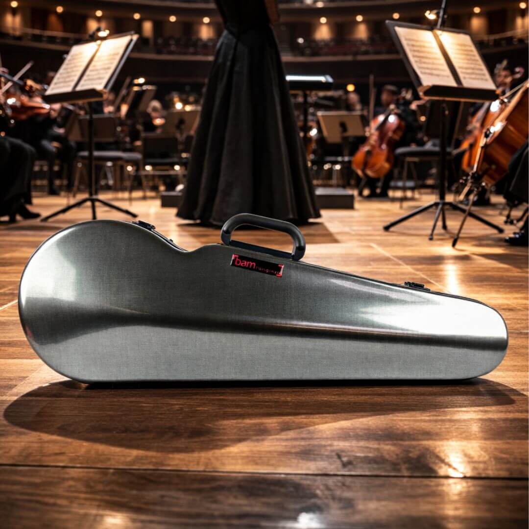 A grey violin case rests on a wooden stage in front of a performing orchestra.