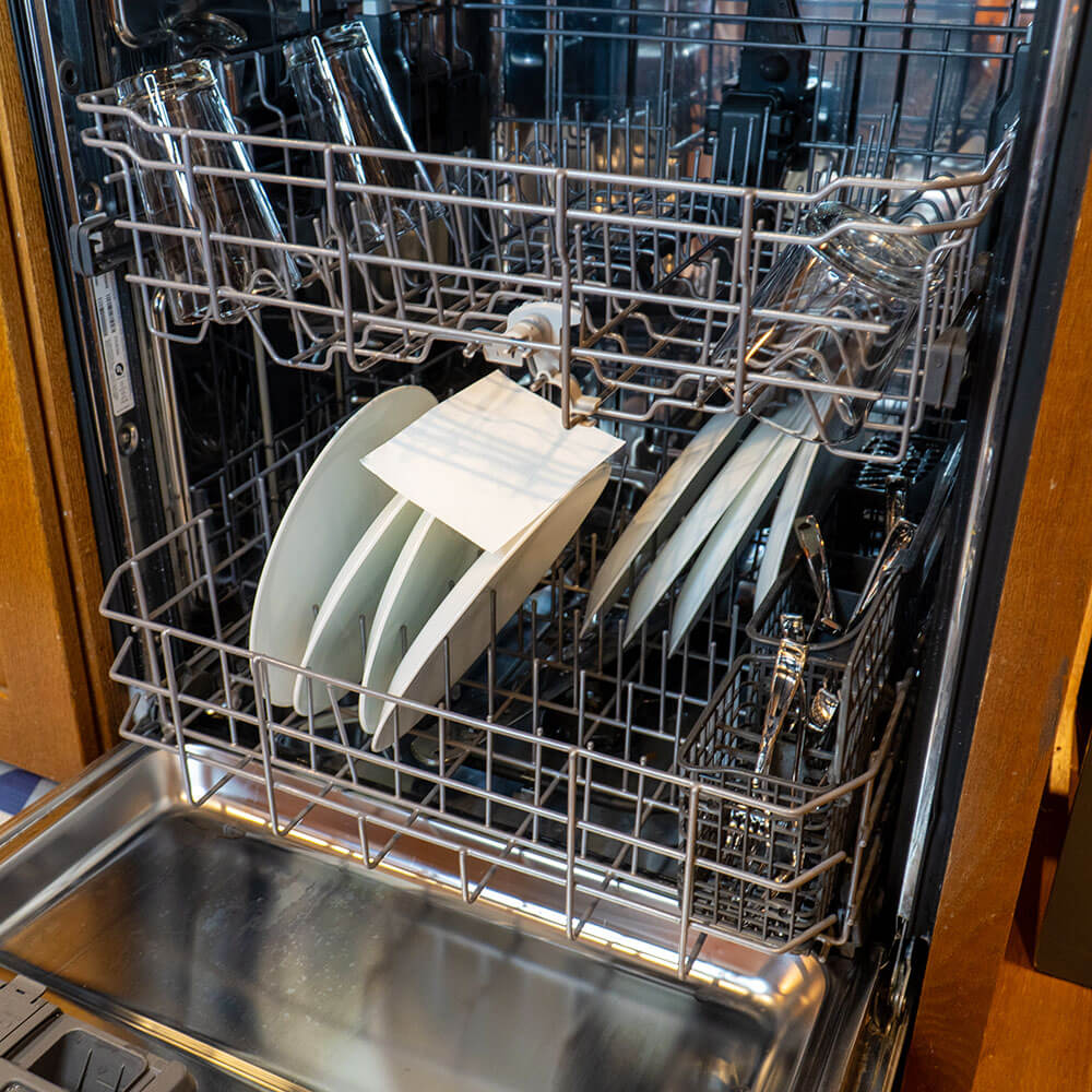 Open dishwasher with dishes, glasses, and cutlery inside.