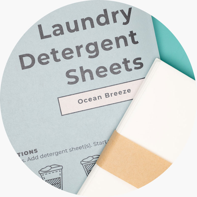 A close-up of Ocean Breeze laundry detergent sheets packaging next to a stack of the sheets.