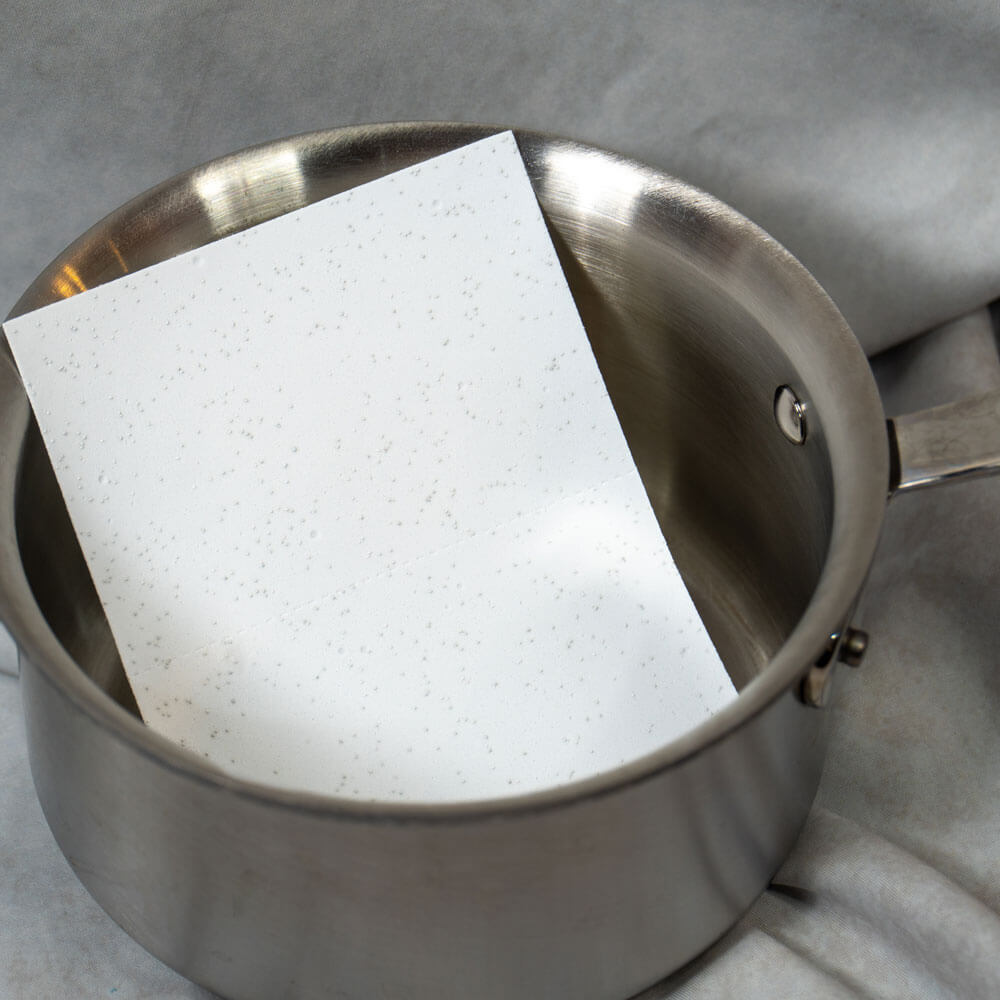 Stainless steel pot with a speckled white paper inside.