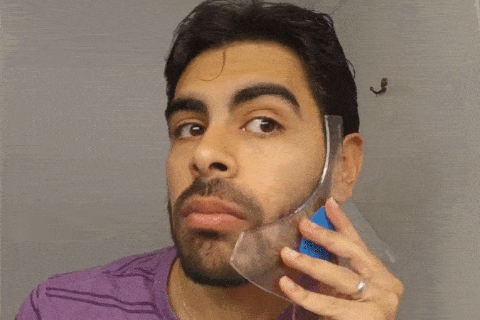 Person using a transparent tool to shape their beard.