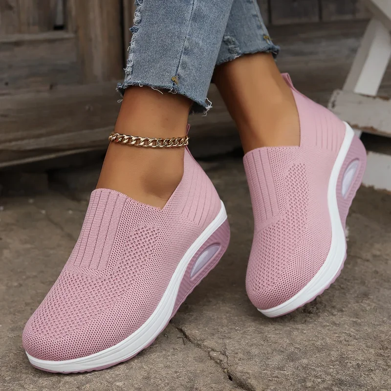 Person wearing pink slip-on sneakers and a gold anklet.