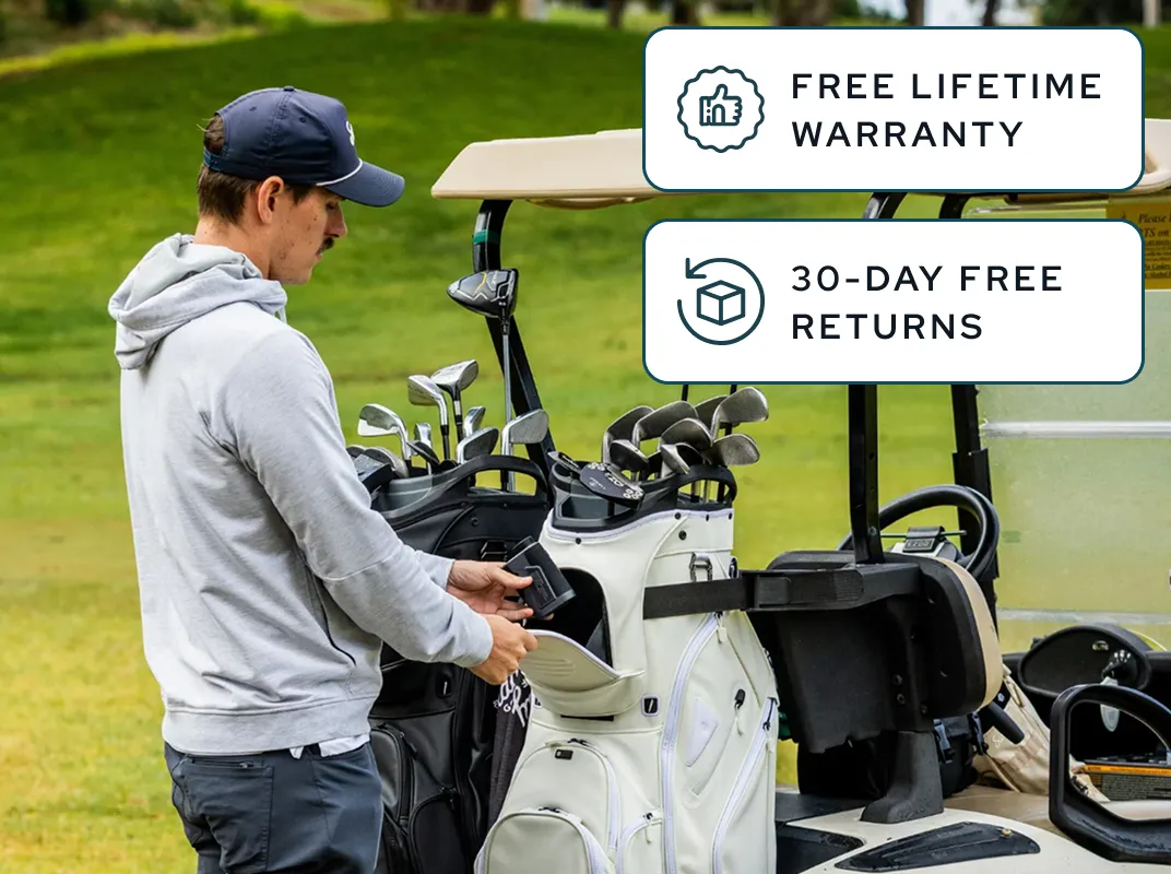 A man in a grey hoodie places an item into a white golf bag on a golf cart.