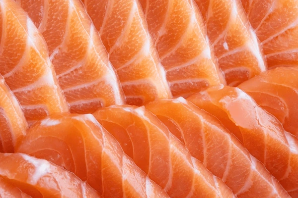 Close-up of fresh, sliced salmon pieces arranged in a pattern.