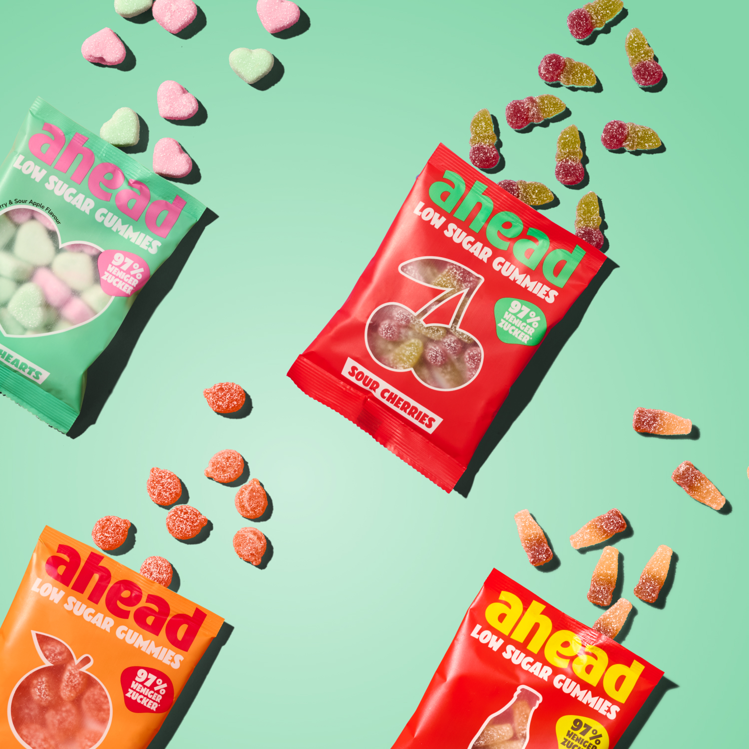 Colorful gummy candy packages and scattered gummies on a green background.