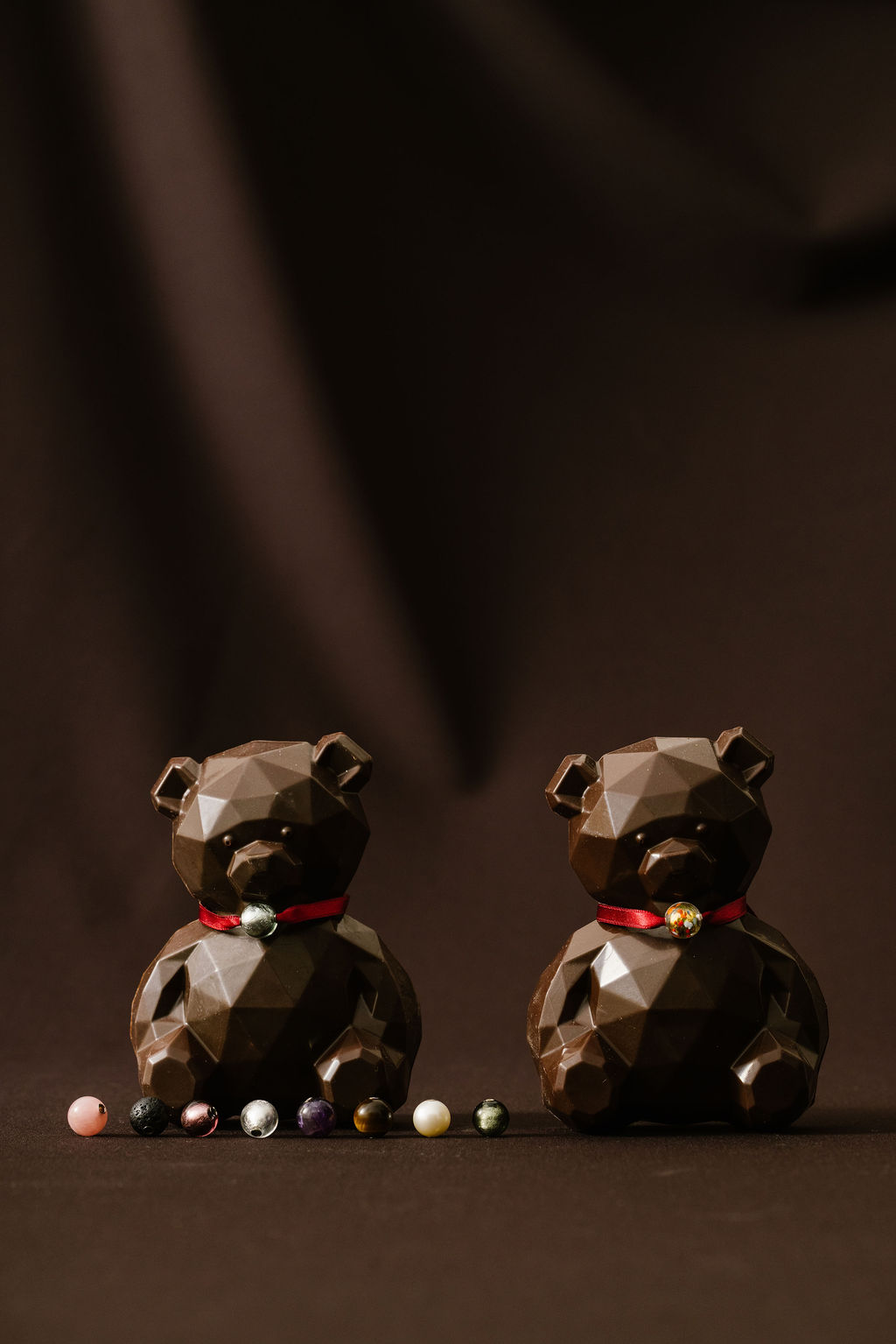 Two geometric bear sculptures with red ribbons, surrounded by colorful spherical objects.