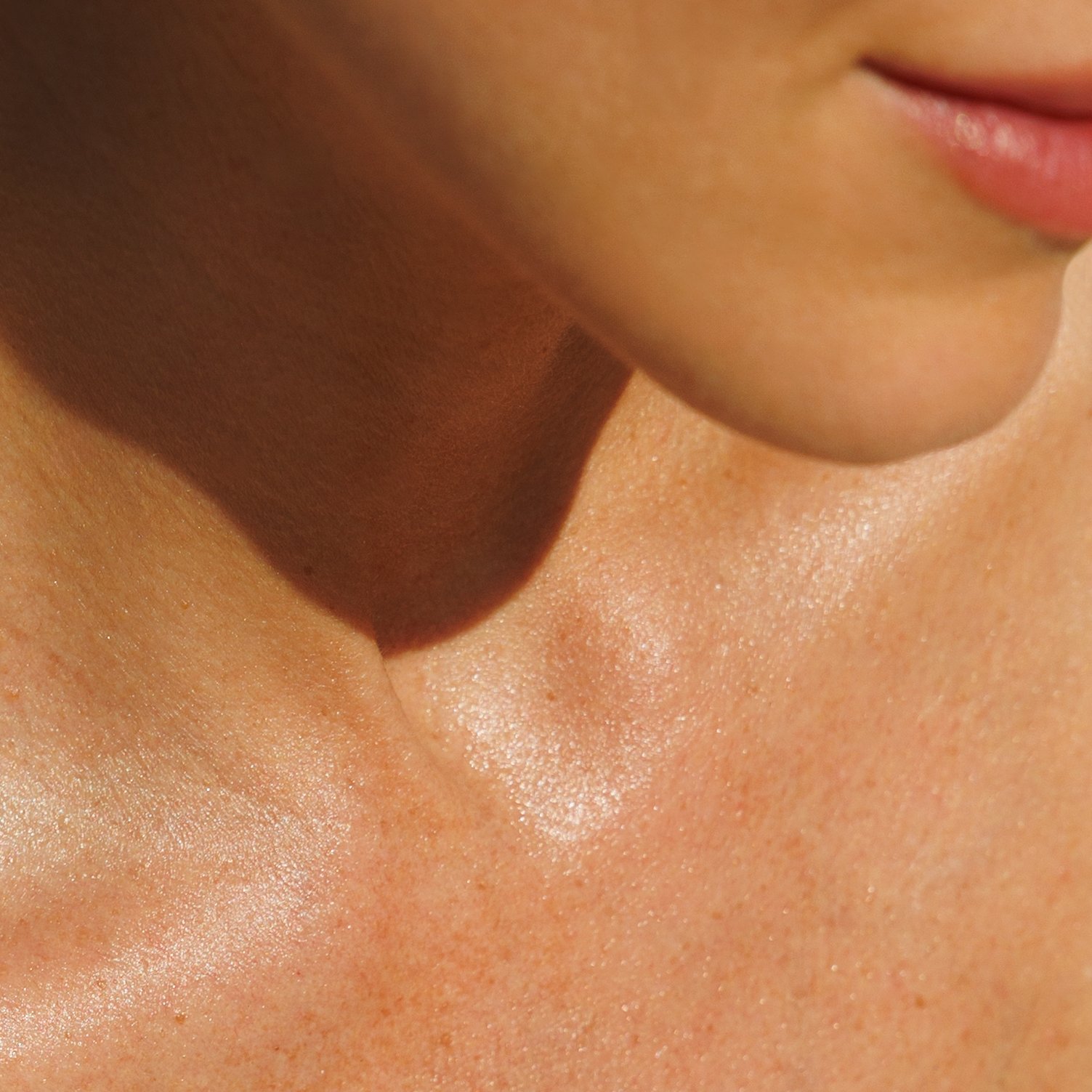 Close-up of a person's neck and lower face with natural lighting.