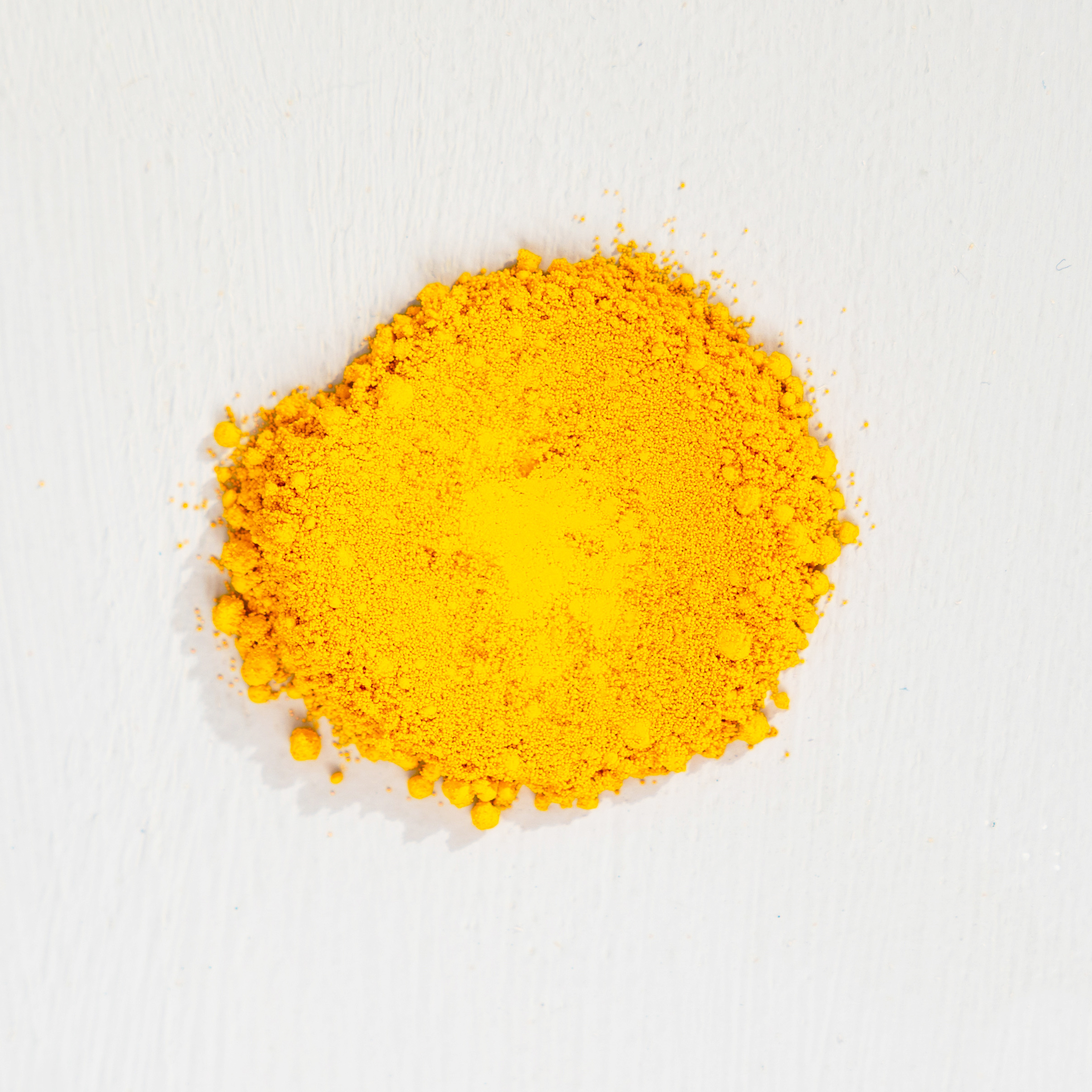 A pile of bright yellow powder on a white surface.