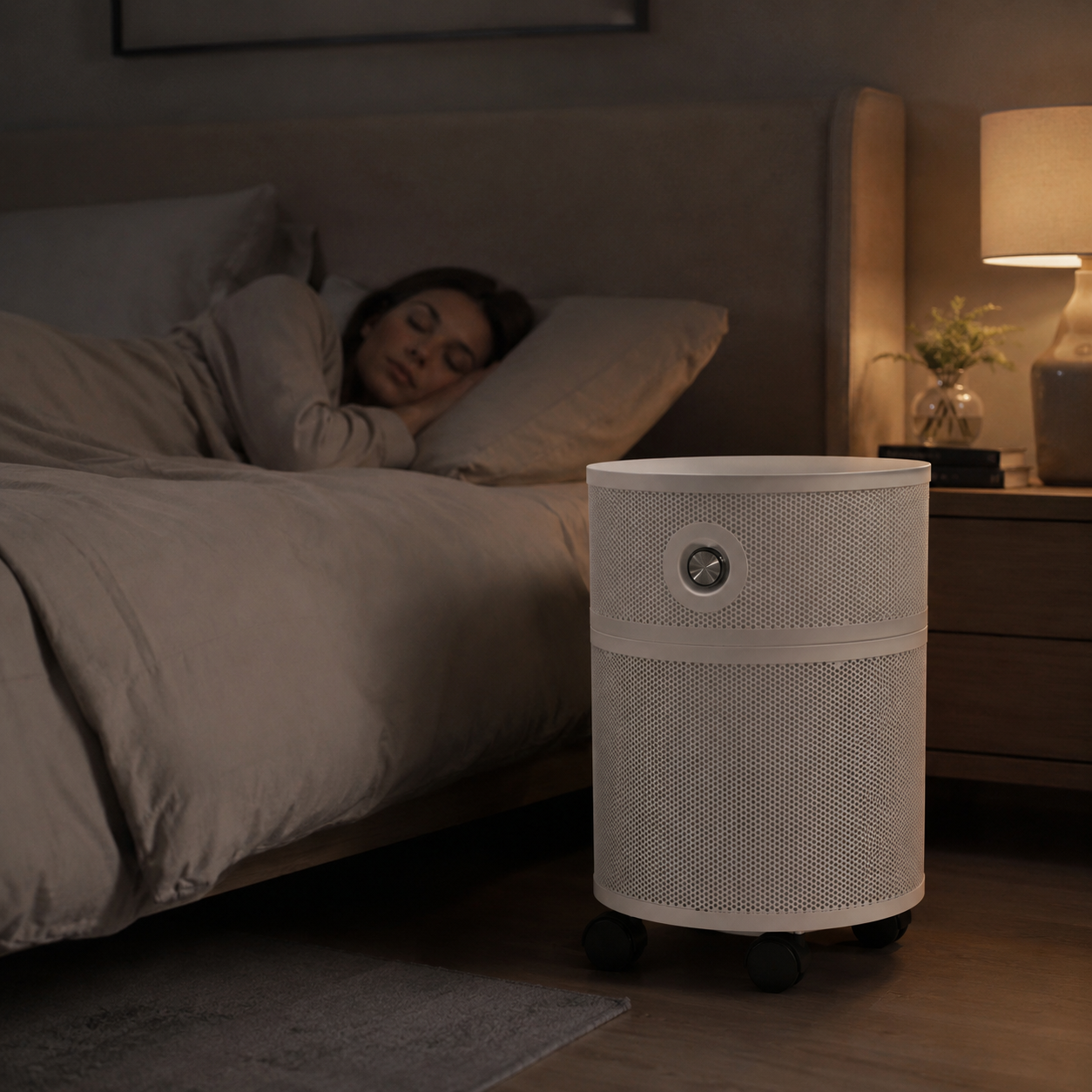 A woman sleeps peacefully in a dimly lit bedroom with a white, cylindrical air purifier in the foreground.