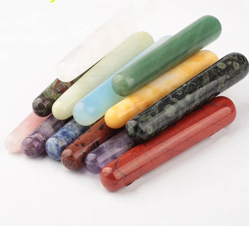 An assortment of smooth, colorful, polished stone wands arranged in a fan on a white background.