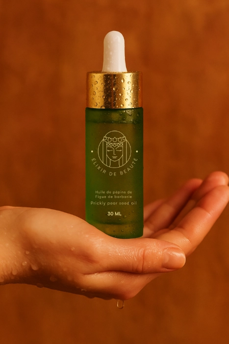 Hand holding a green bottle with a dropper, labeled 'Prickly pear seed oil.'