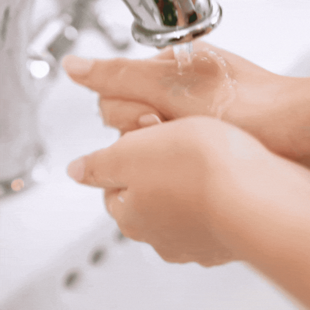 Person washing hands under running water.