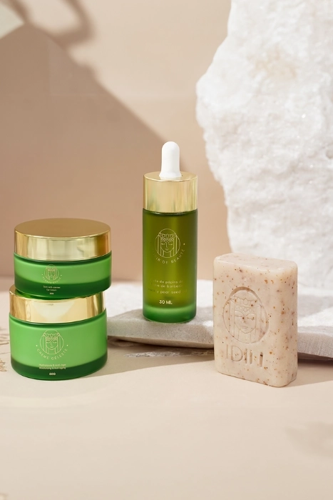 Green skincare products and a bar of soap on a beige background.