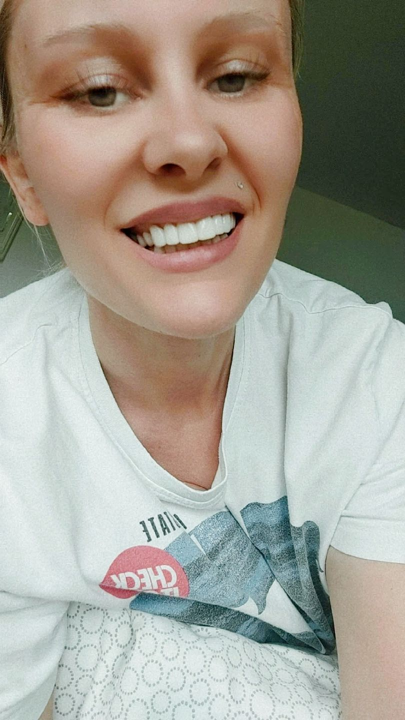 A person smiling while wearing a white shirt.