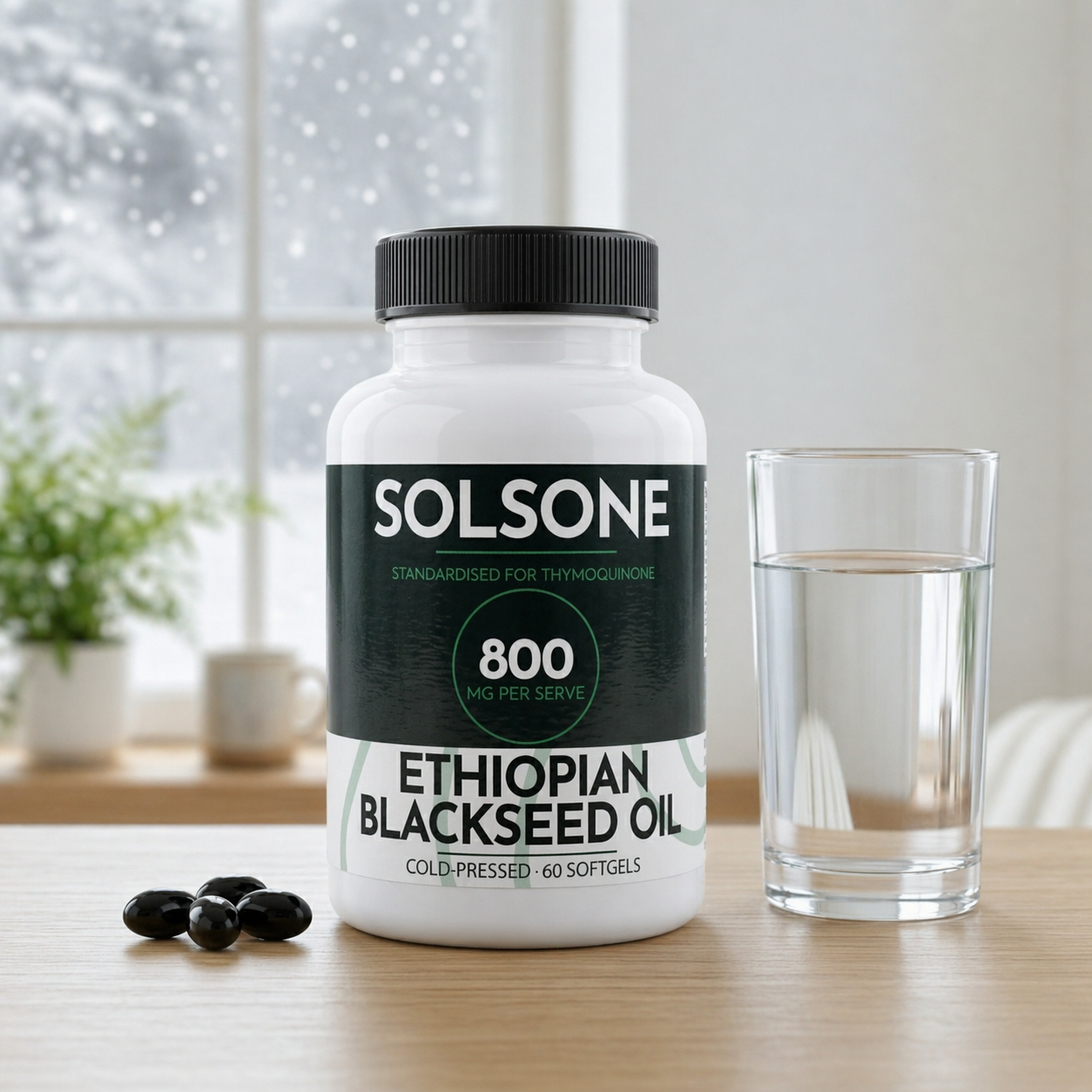 A bottle of Solsone Ethiopian Blackseed Oil supplements on a table with a glass of water and softgels.