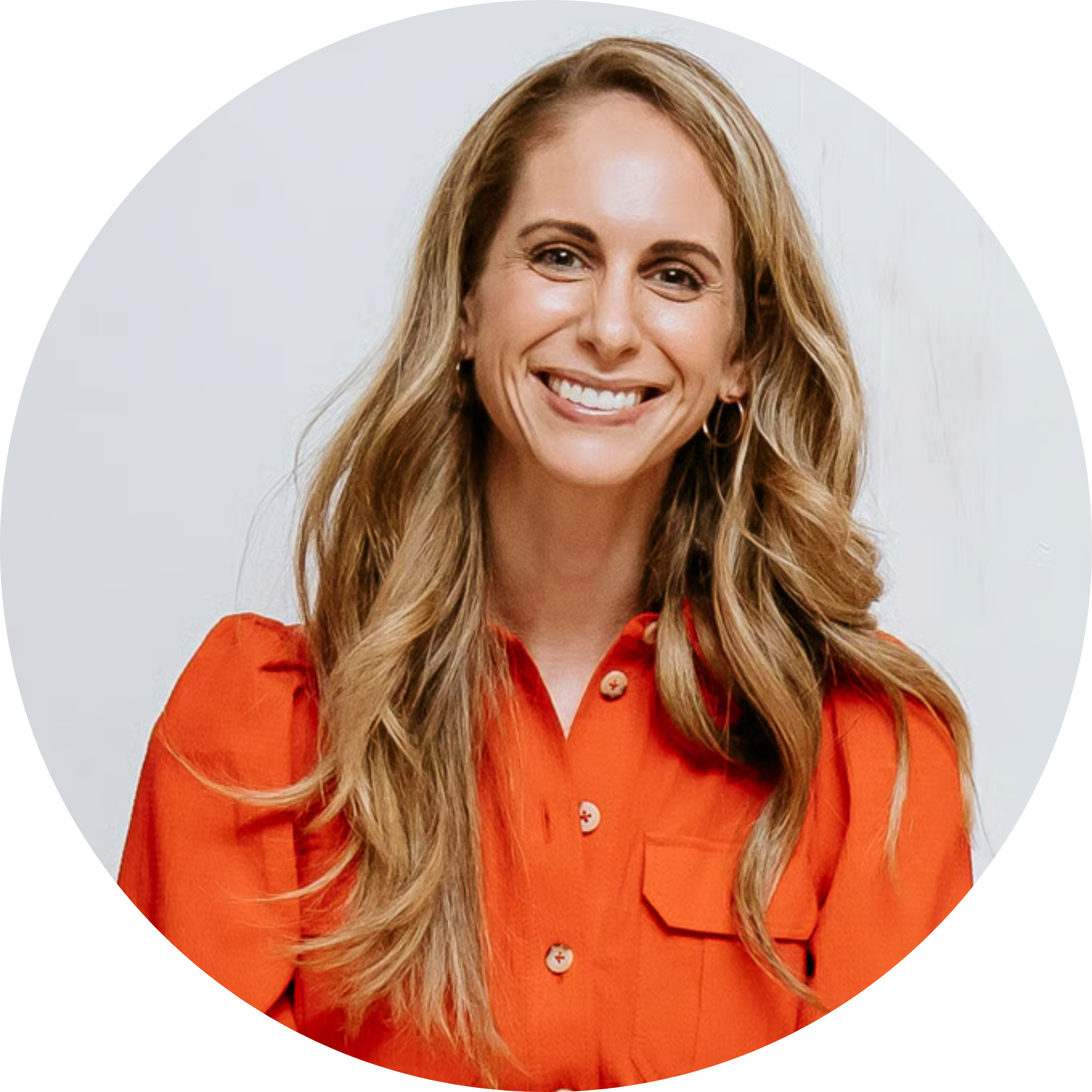 A smiling woman with long blonde hair wearing a bright orange button-up shirt, in a circular frame.