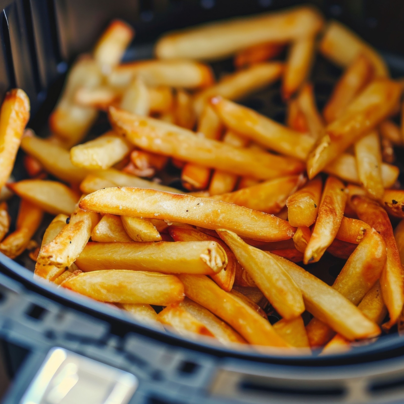 Golden-brown French fries in an air fryer basket.