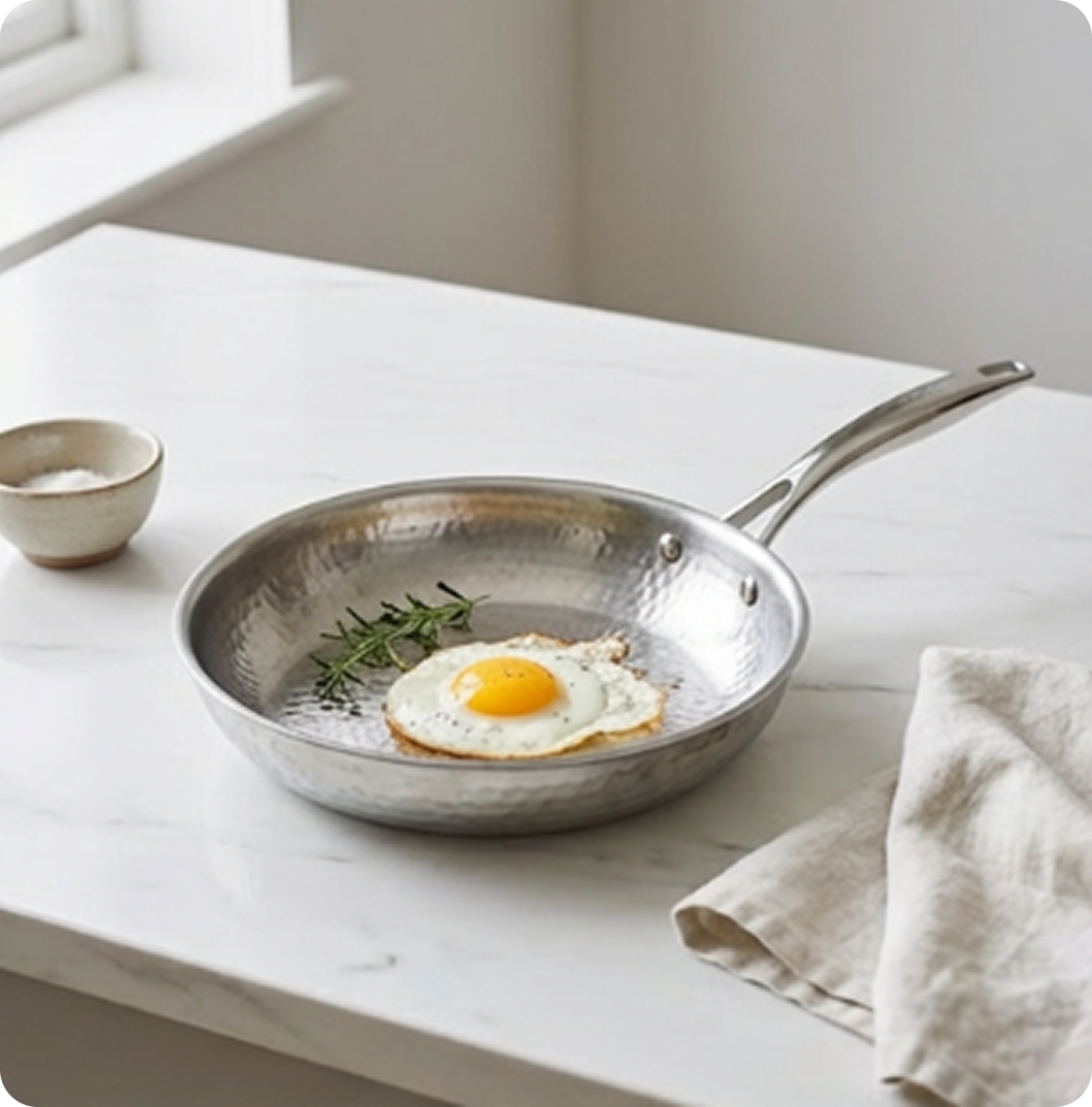 Chicken breasts and asparagus cooking in a stainless steel skillet on a glass cooktop in a modern kitchen.