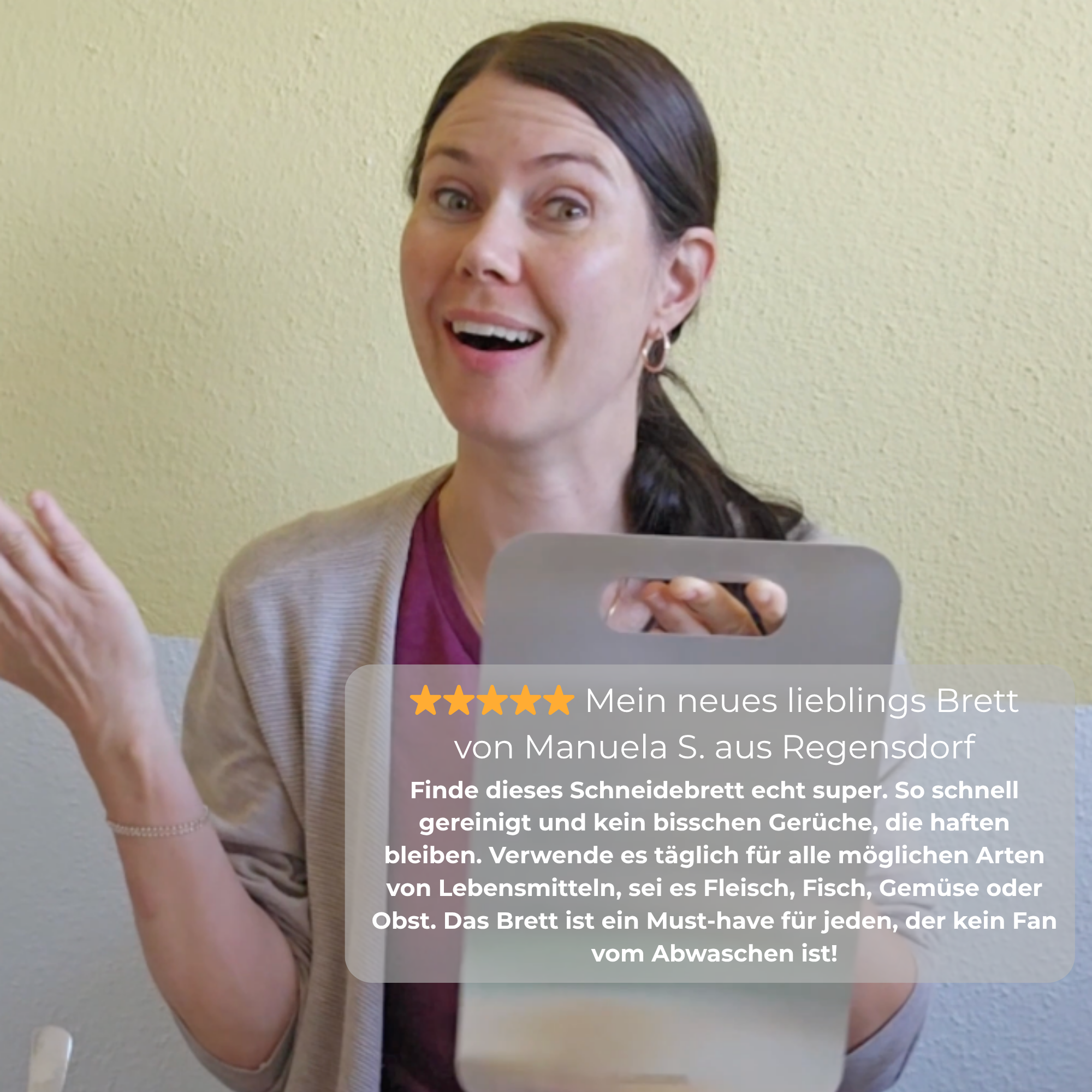A woman with a happy expression holds a grey cutting board with an overlaid product review in German.