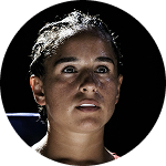 A close-up circular portrait of a woman with a sweaty, intense expression against a dark background.