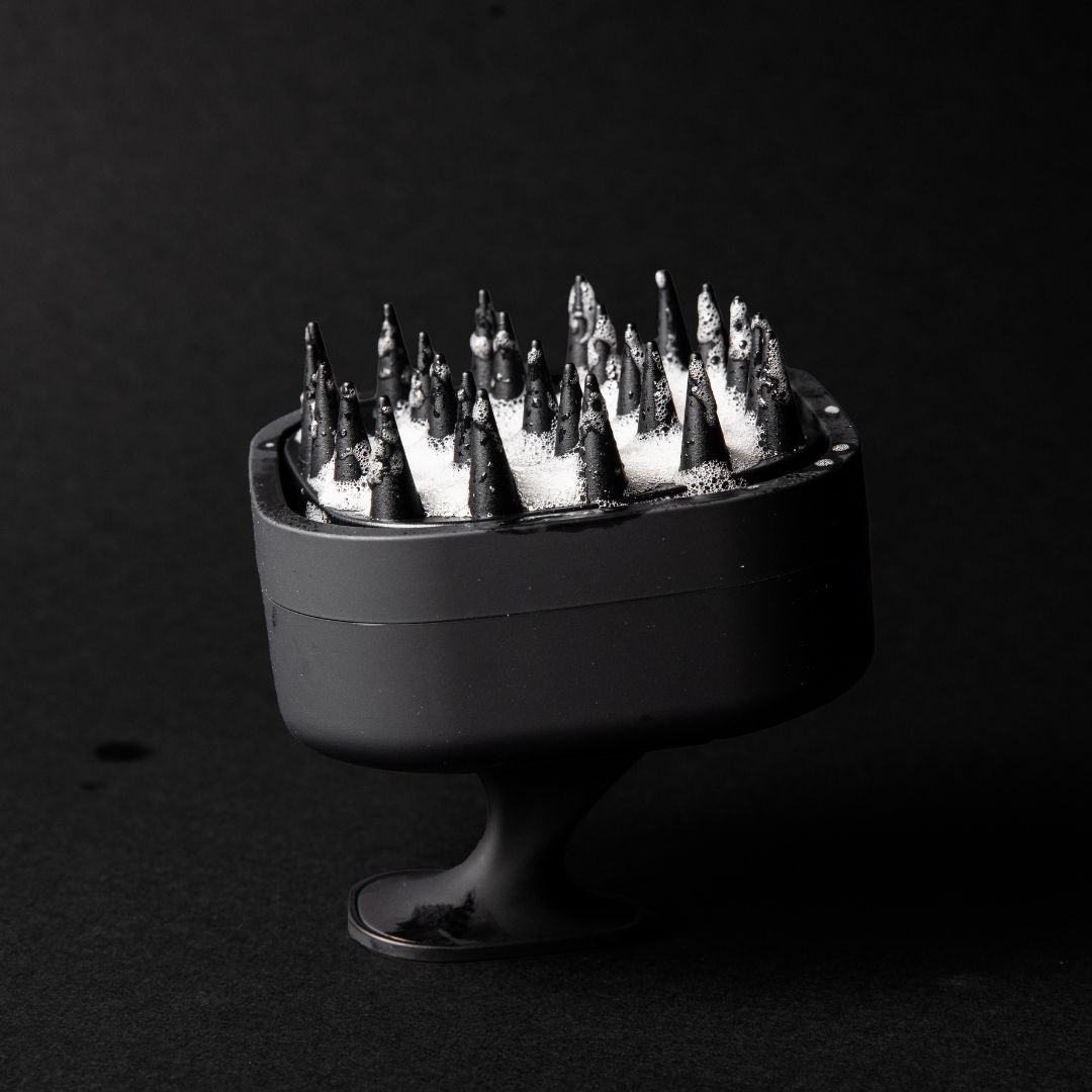 Black spiked object with foam on a dark background.