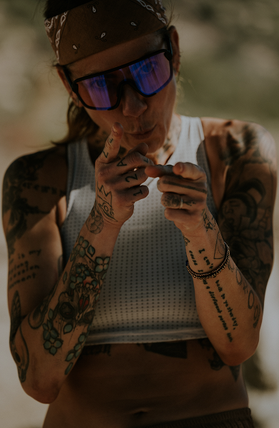 Person with tattoos and sunglasses pointing with fingers.