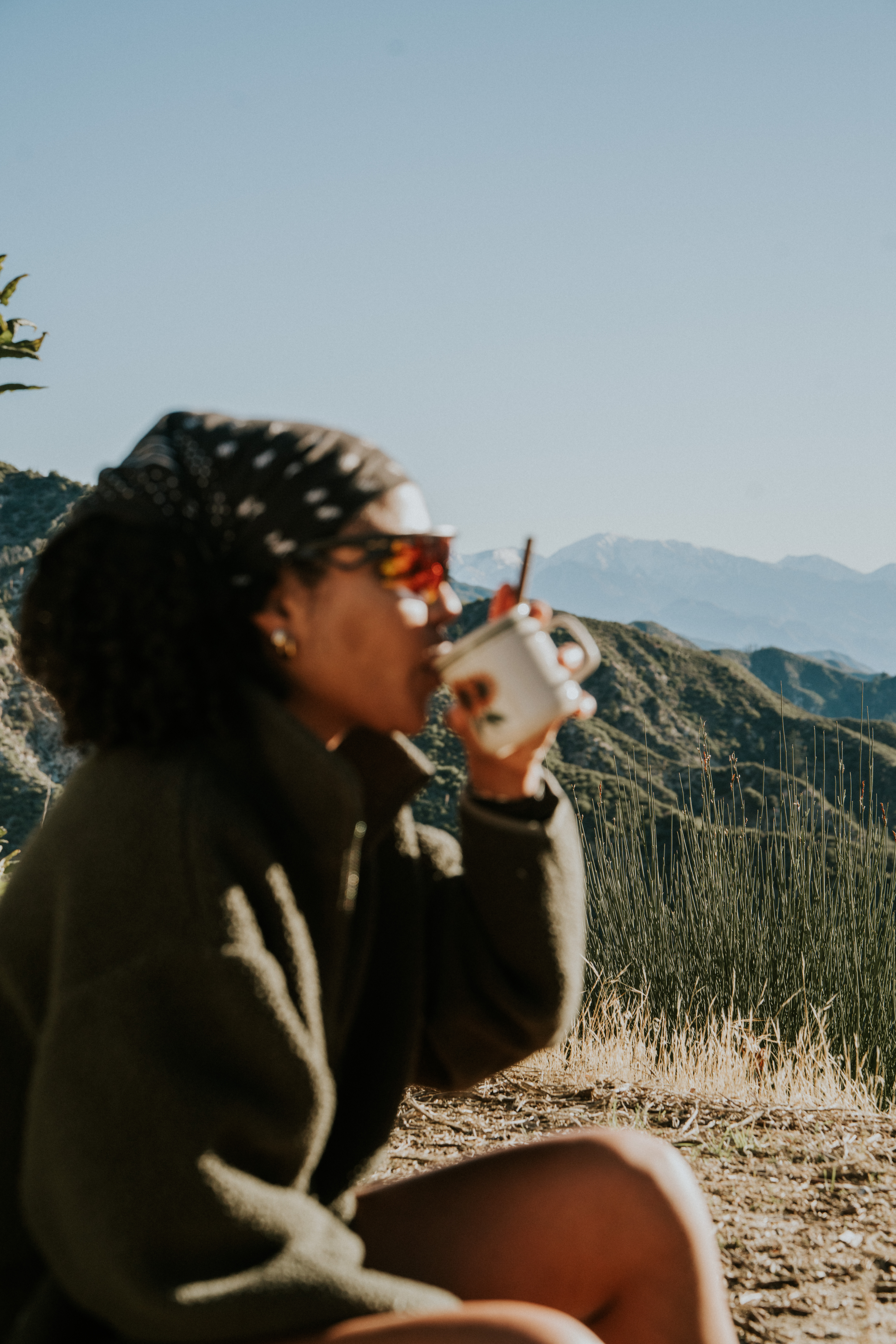Person drinking from a cup with scenic mountain background.