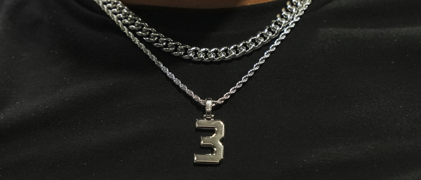 Person wearing a silver chain with a number 3 pendant.