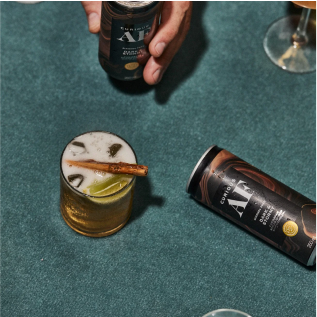 A cocktail with garnishes next to a can on a green surface.