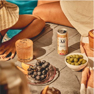 Poolside snacks with grapes, olives, drinks, and a beverage can.
