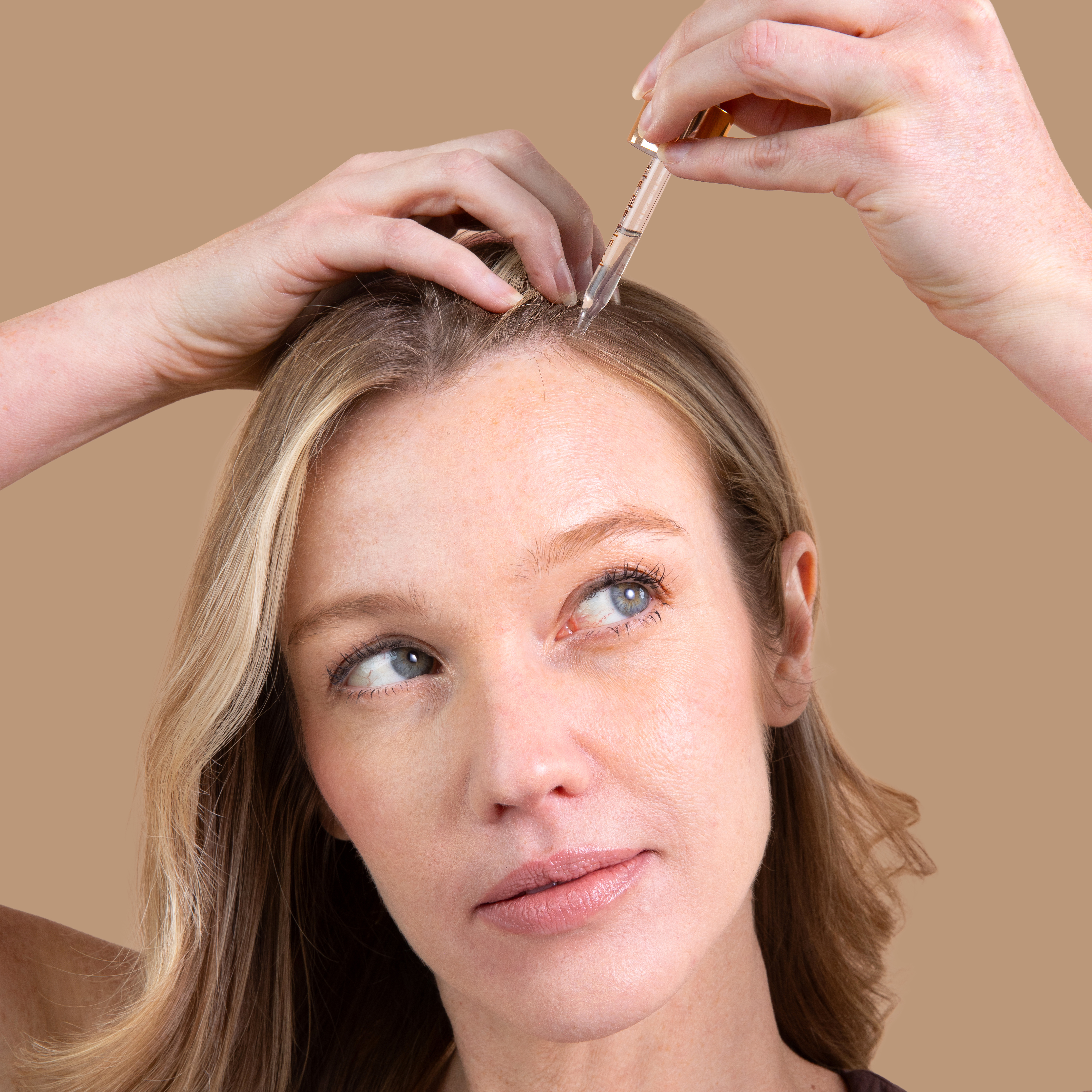 A woman applies ProGRO Density+ Hair Serum to her scalp