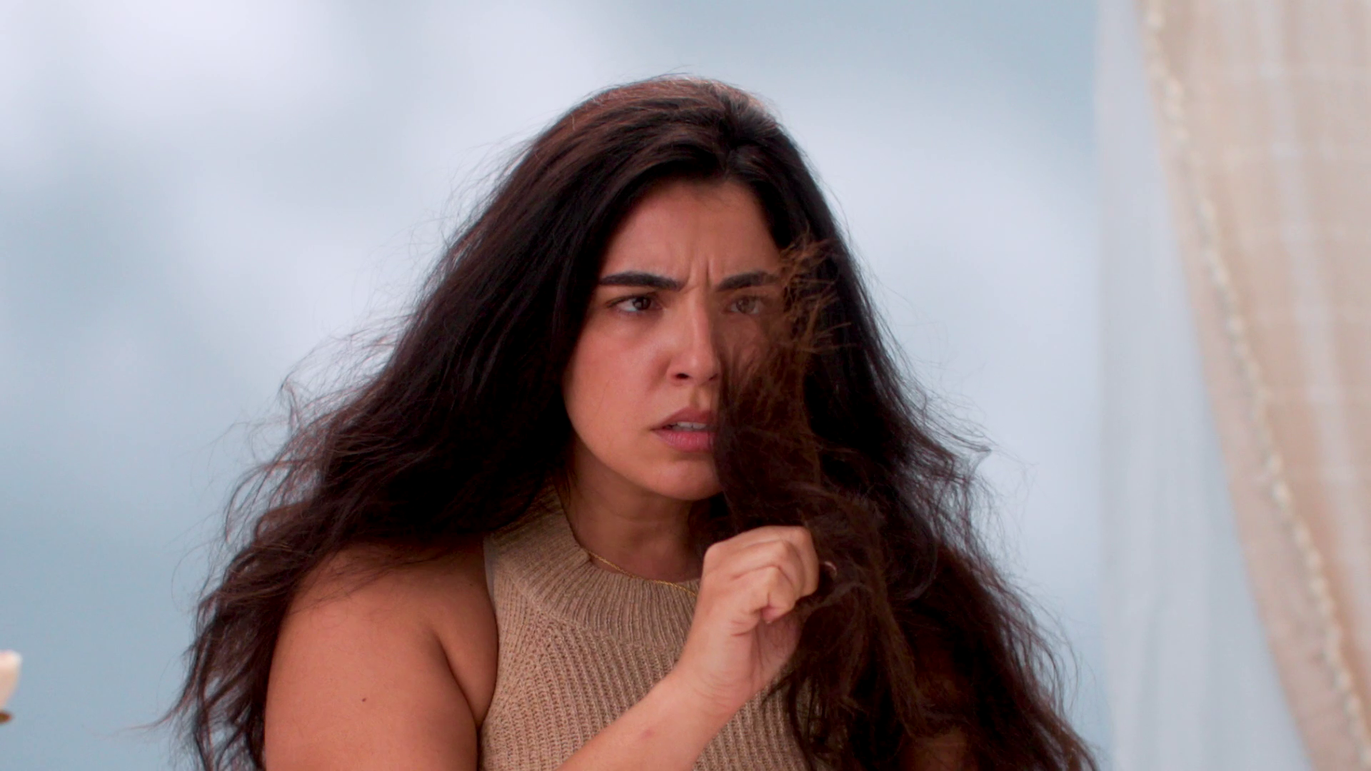 Person examining their hair with a concerned expression.