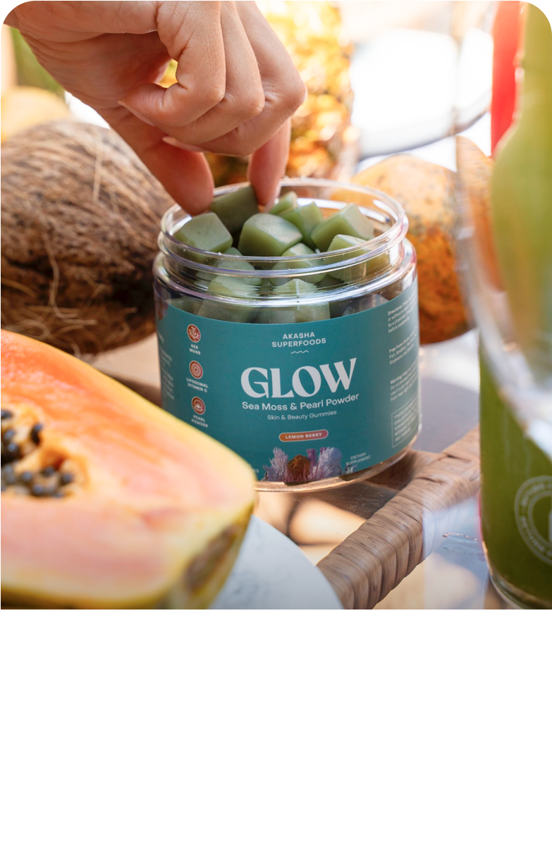 Hand picking green gummies from a jar labeled 'Glow' with fruits in the background.