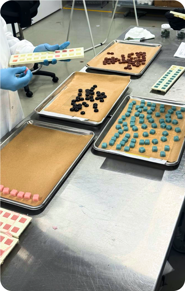 Trays of colorful candies on a metal table in a laboratory setting.