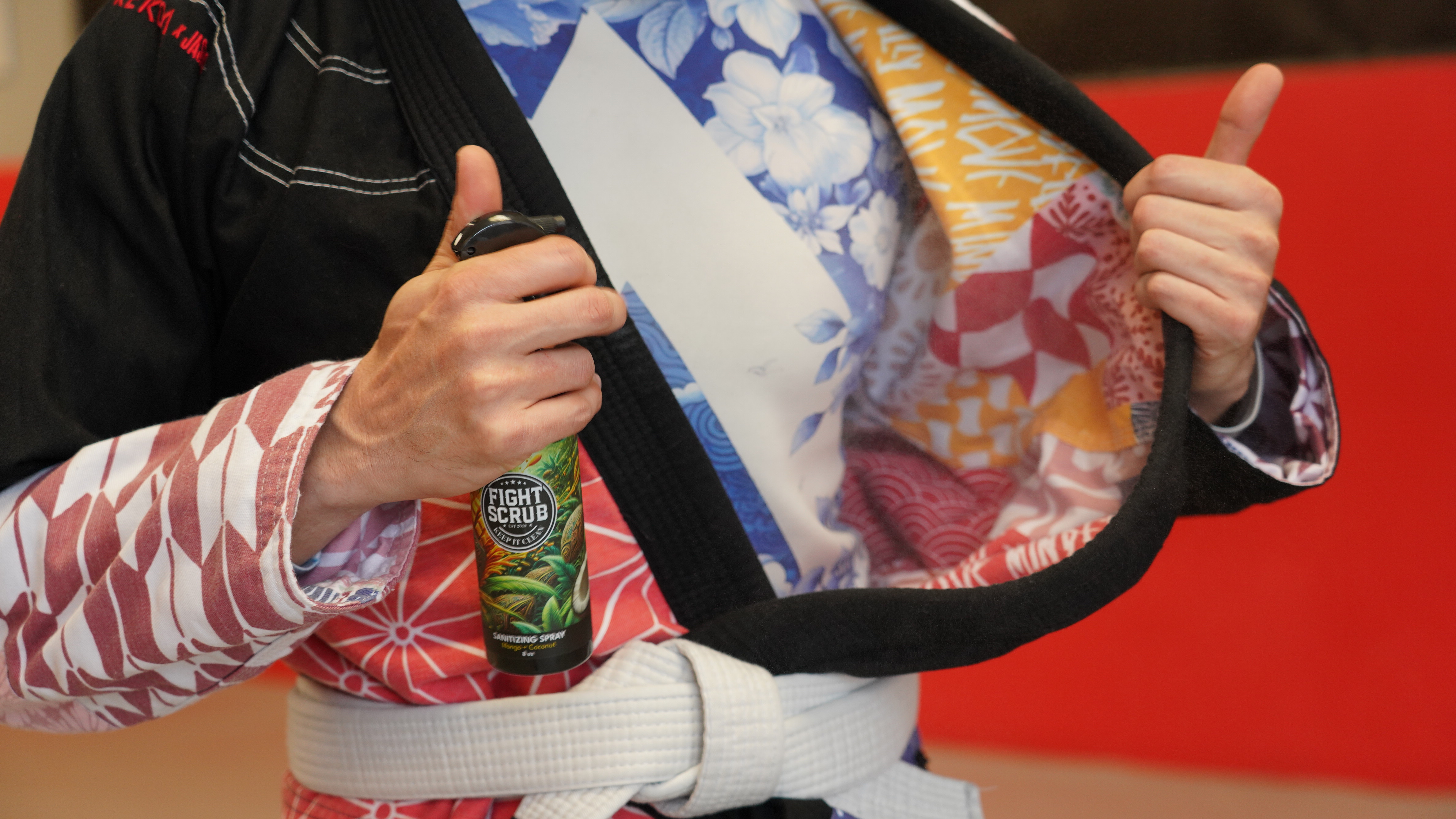 Person holding a can of 'Fight Scrub' spray, wearing a colorful martial arts gi.