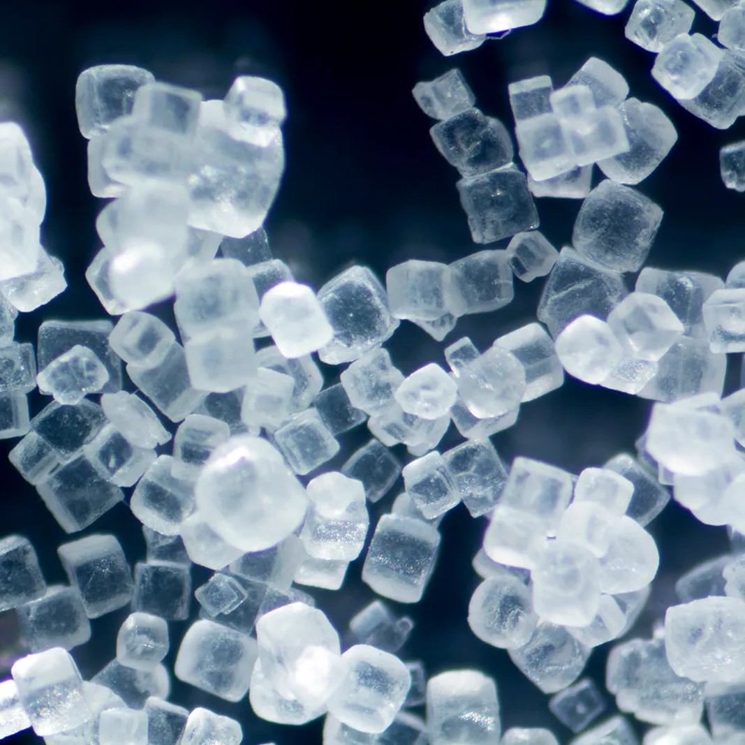 Close-up of white crystal cubes, resembling sugar or salt granules.