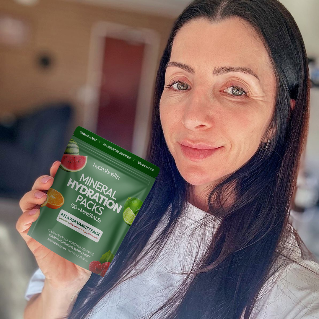 Person holding a packet of mineral hydration packs, smiling indoors.