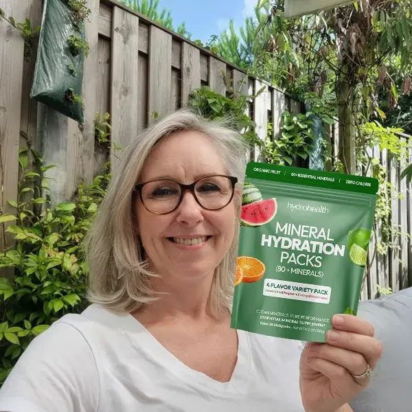 Person holding a pack of mineral hydration packs in a garden setting.