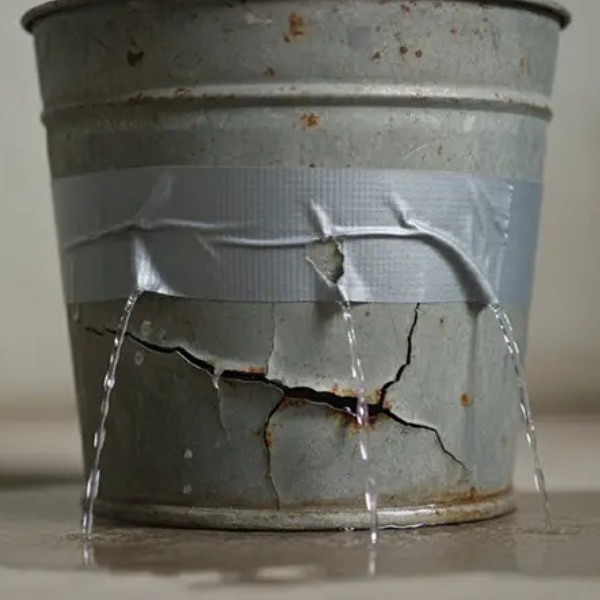 Leaking metal bucket with cracks and duct tape, water pouring out.