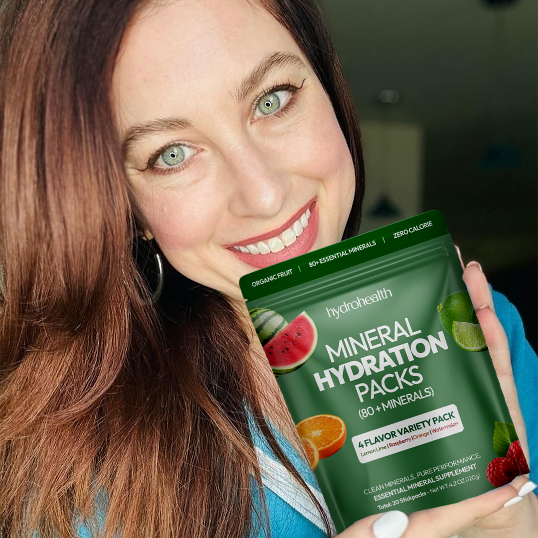 A smiling person holding a pack of mineral hydration packs.