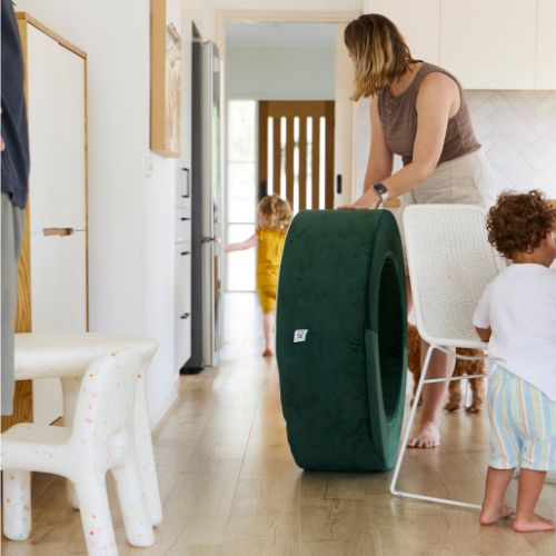 Woman and children in a living room with a large green cushion.
