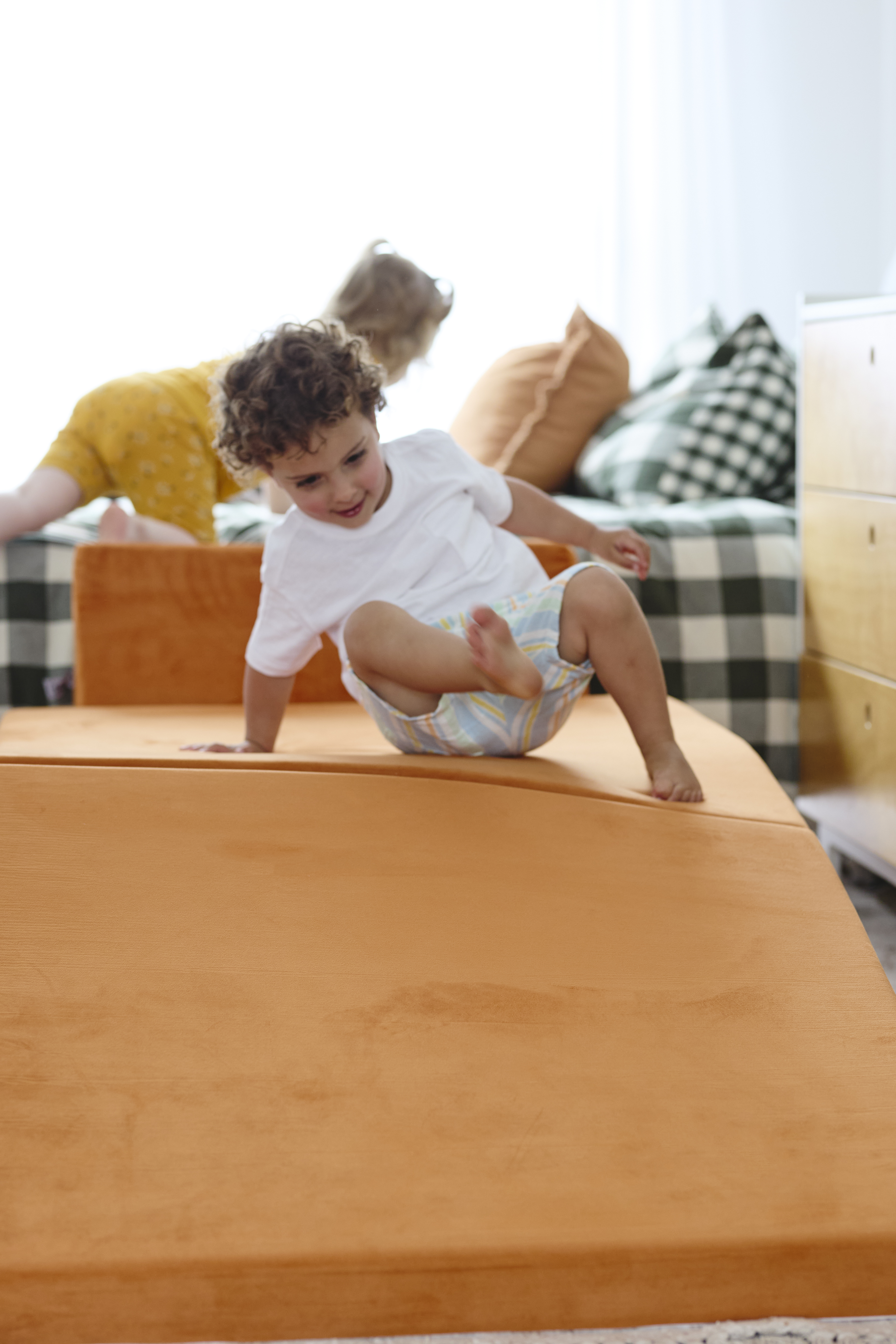 Child playing on an orange foam mat indoors.