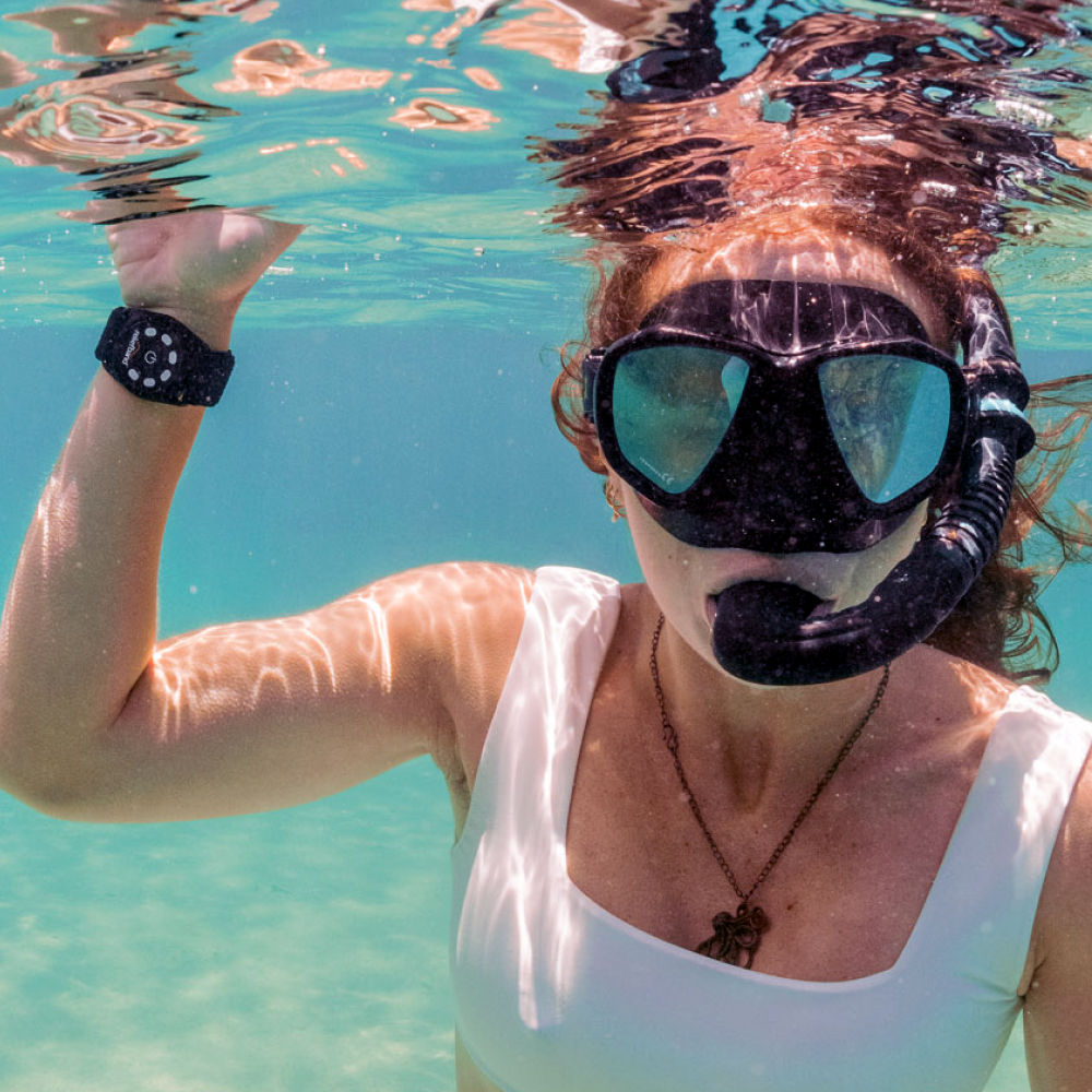 Person snorkeling underwater wearing a mask and snorkel in clear blue water.