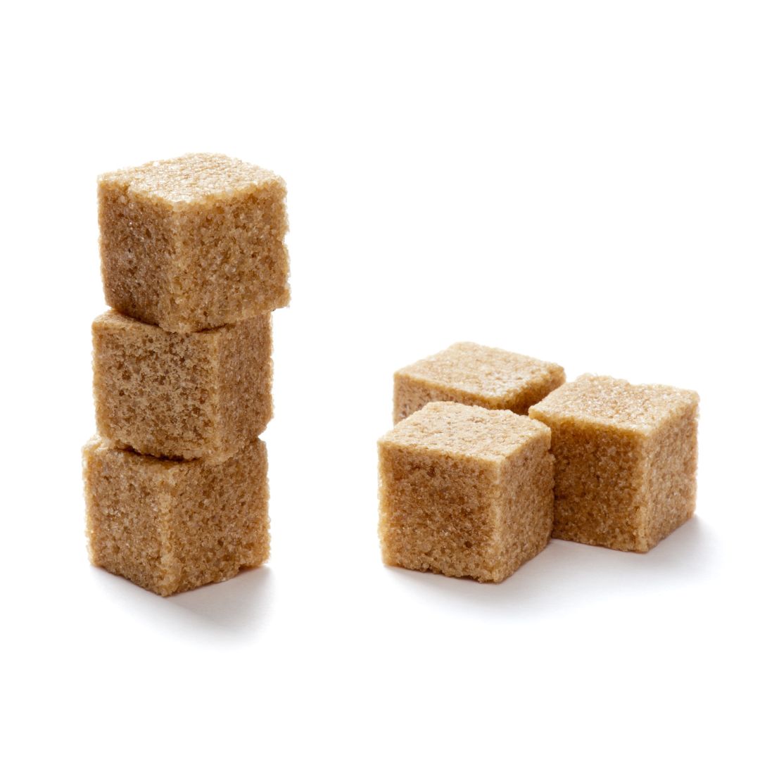 Five brown sugar cubes, three stacked and two beside each other, on a white background.