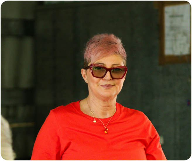 Person with short pink hair wearing a red shirt and sunglasses.