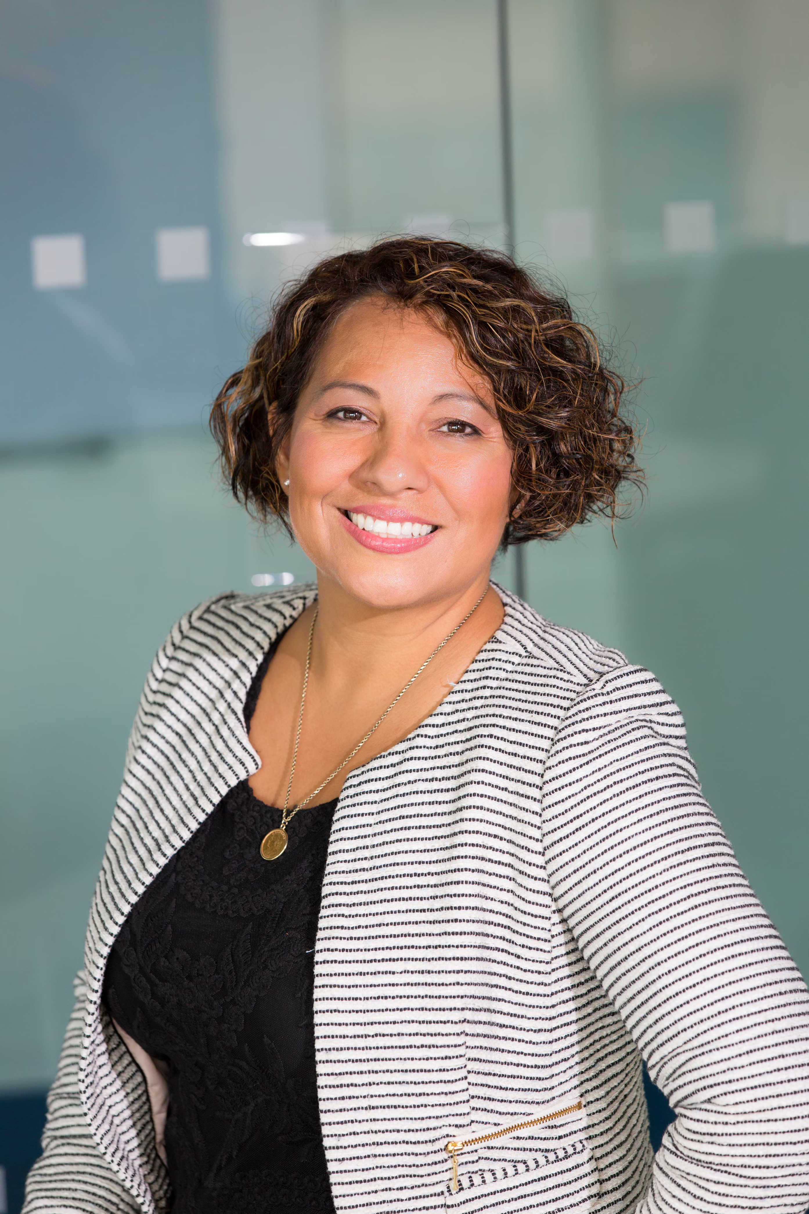 Smiling woman in business attire, standing in an office environment.