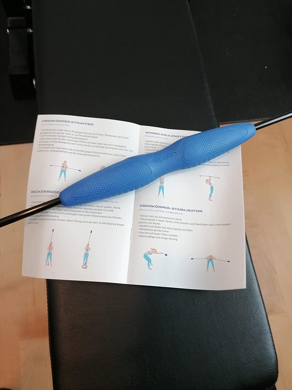 Exercise manual with blue barbell placed on it, illustrating workout poses.