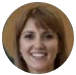 A circular, cropped headshot of a smiling woman with brown hair.