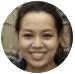 A circular, close-up photo of a smiling woman with dark hair, looking at the camera.