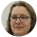 A circular, low-resolution headshot of a person with brown hair and glasses.